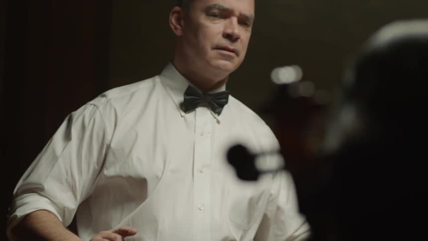Man wears a bow tie as he conducts an orchestra