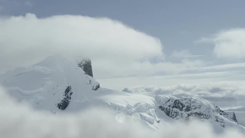 The clouds slowly move over the snow covered mountains