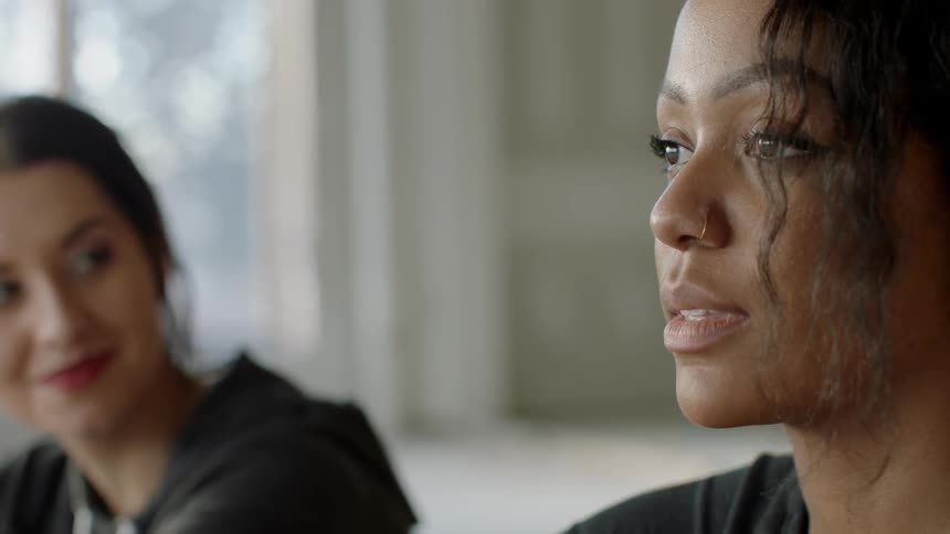 Woman smiles as she watches another woman turn her head away