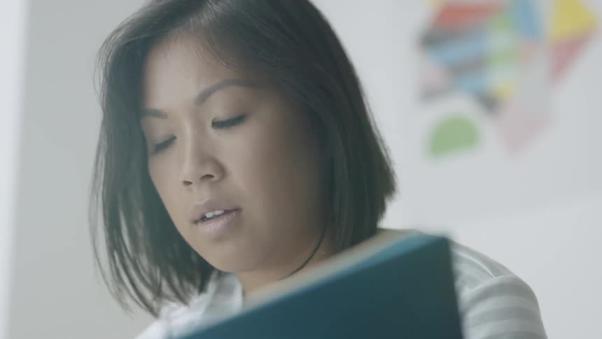 A woman is looking to the side concentrating then takes notes