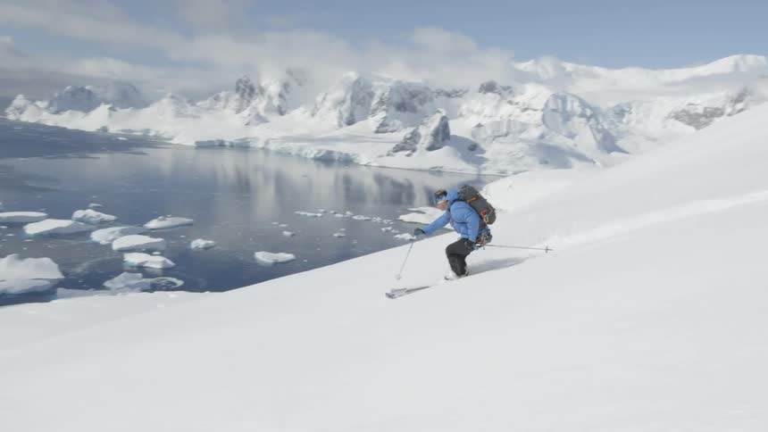 A skier glides down a snowy mountainside