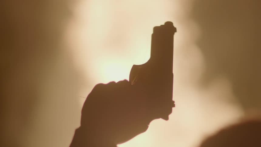 A person is waving their gun in the air as a fire rages