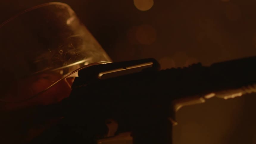 A man stands next to a fire with a gun