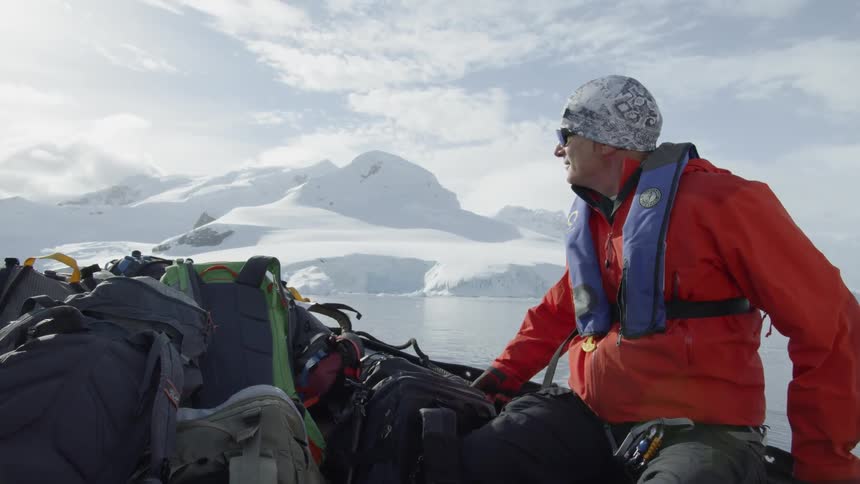 A man sits on the side of the raft looking at the icy shores