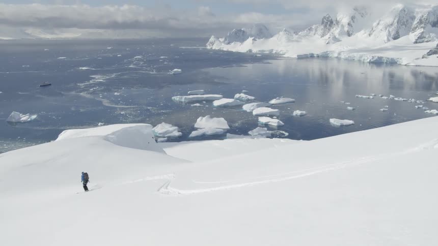 A skier glides down a snowy mountainside