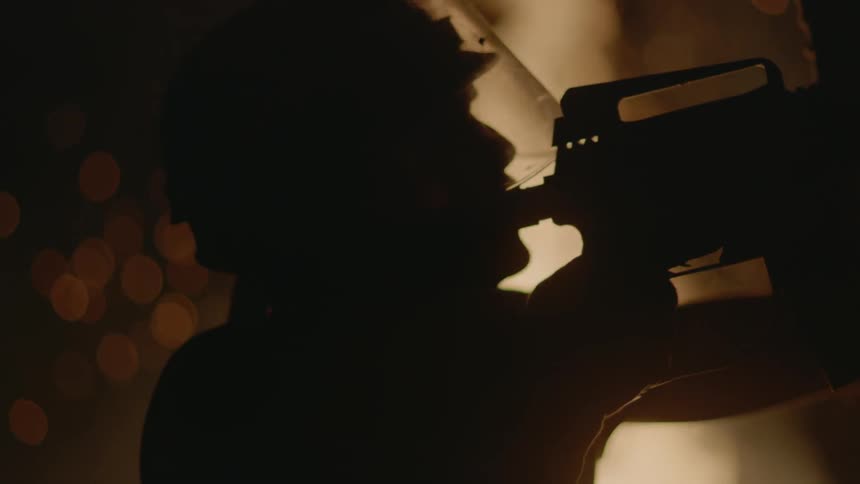 A man points a rifle in a dark area by a fire