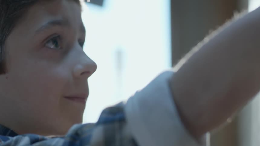 Kid raises his arm and looks up smiling