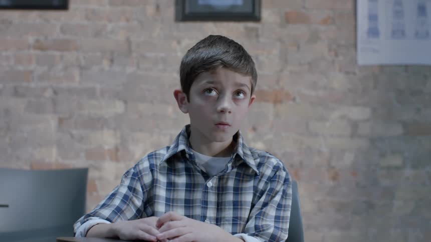 A boy sitting at a desk looks up