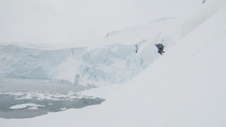 A skiers glides down a snowy mountainside