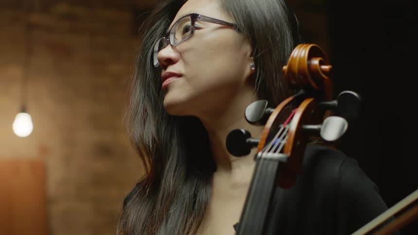 A woman  looks up while holding a cello