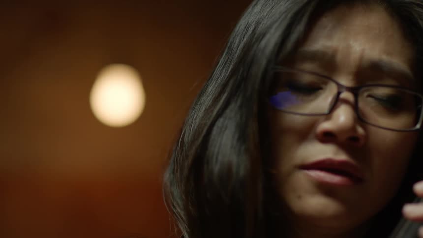 A woman closes her eyes while playing a cello