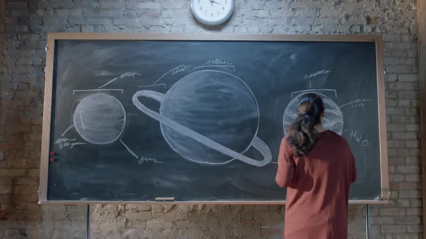 A teacher writes on a chalkboard