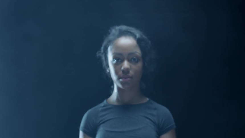 Woman comes into focus standing in a dim room