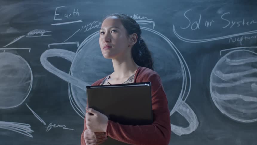 A teacher stands in front of a chalkboard