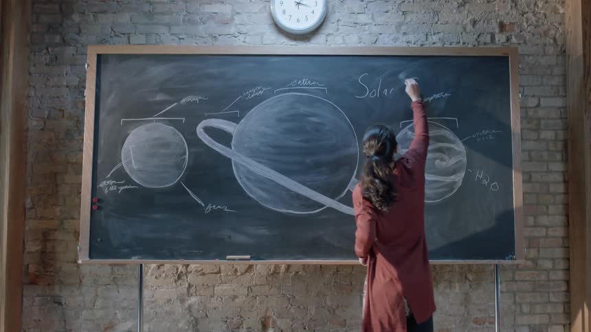 A woman is writing on the large chalkboard