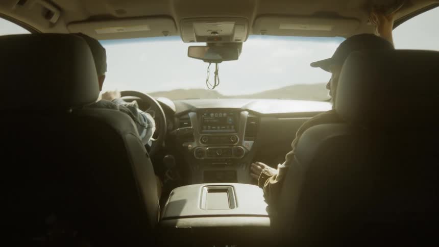 Man drives a vehicle while talking to his passenger