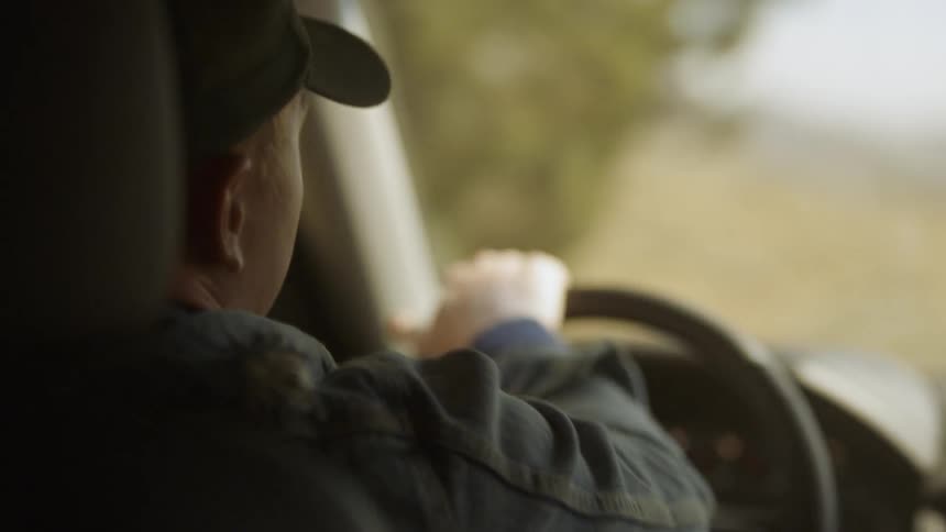 A man taps the steering wheel while driving