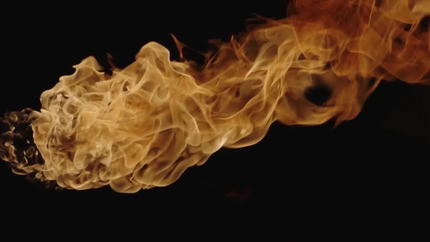 The fire flares and begins to spread in the dark