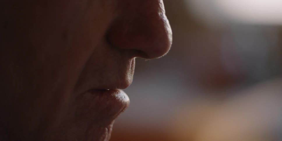 An elderly man has his eyes closed