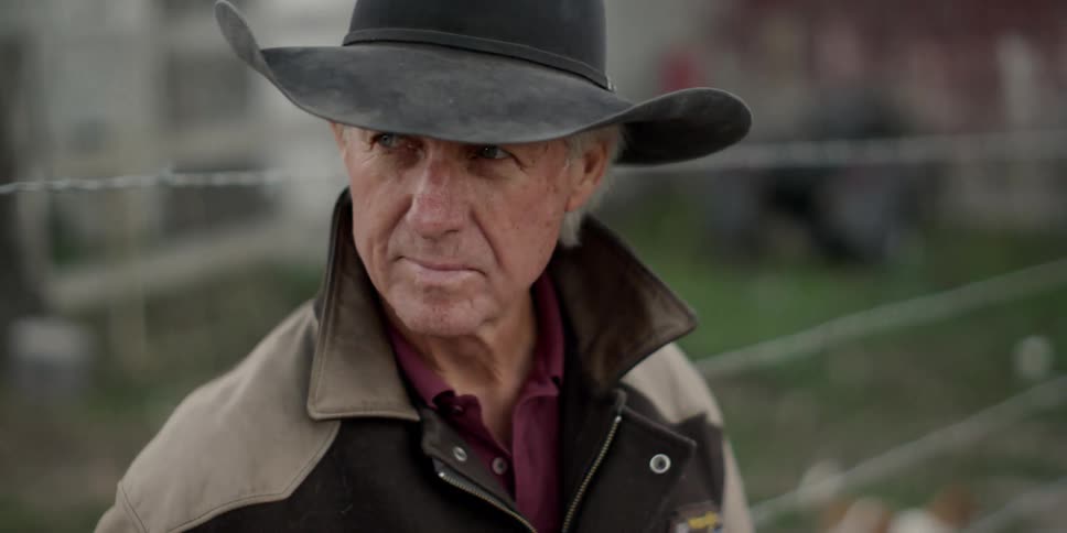 A man stand by a barbed wire fence