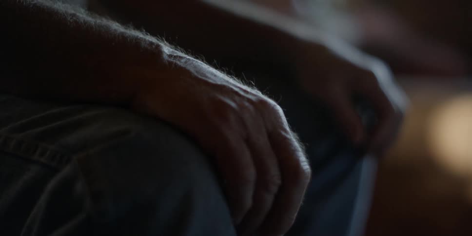 A man sits with his hands on his knees