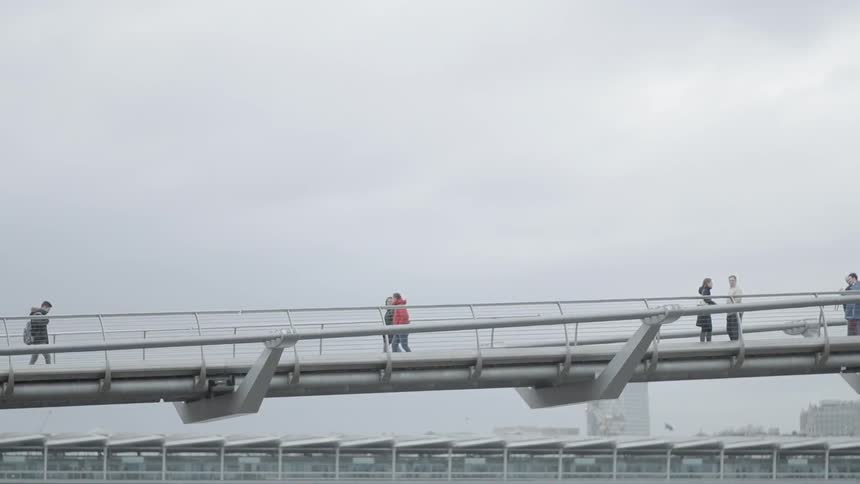 People walk on a bridge on a cloudy day