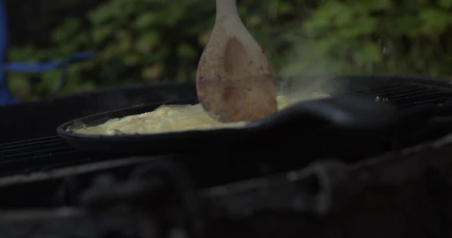 A person is mixing some eggs in the pan outside