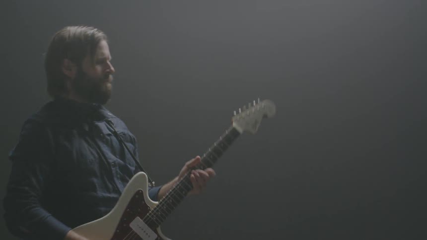 A man plays guitar in a dim room