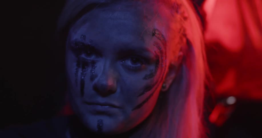 A woman wears paint on her face in the dark