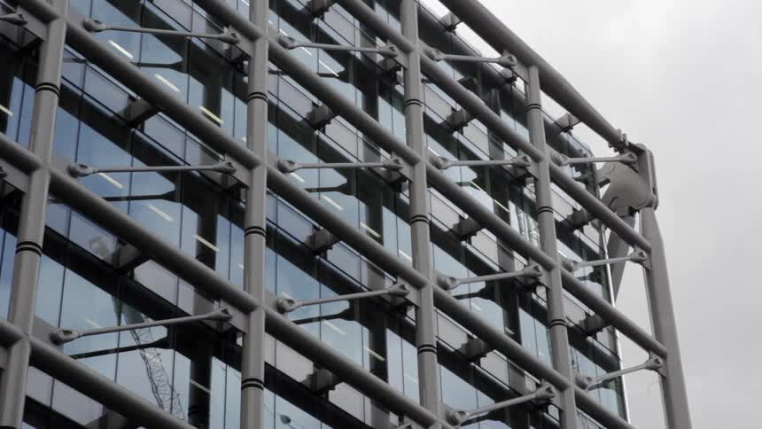 The windows of an office building are reflecting a cloudy daytime sky