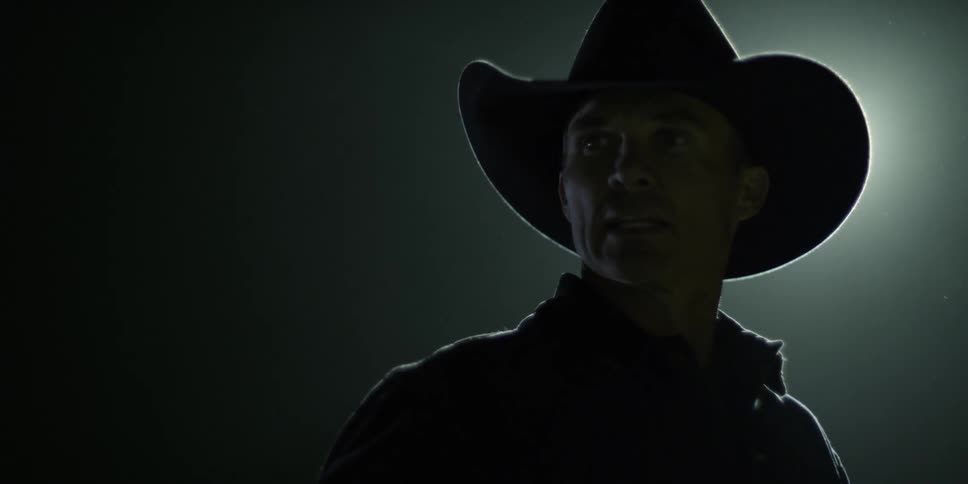A cowboy stands outside at night