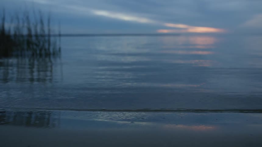 The waves slowly hit the shore at sunset