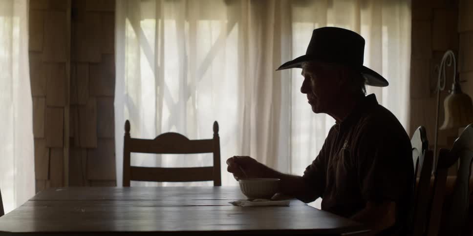 A man is sitting at his table eating from a bowl in daylight