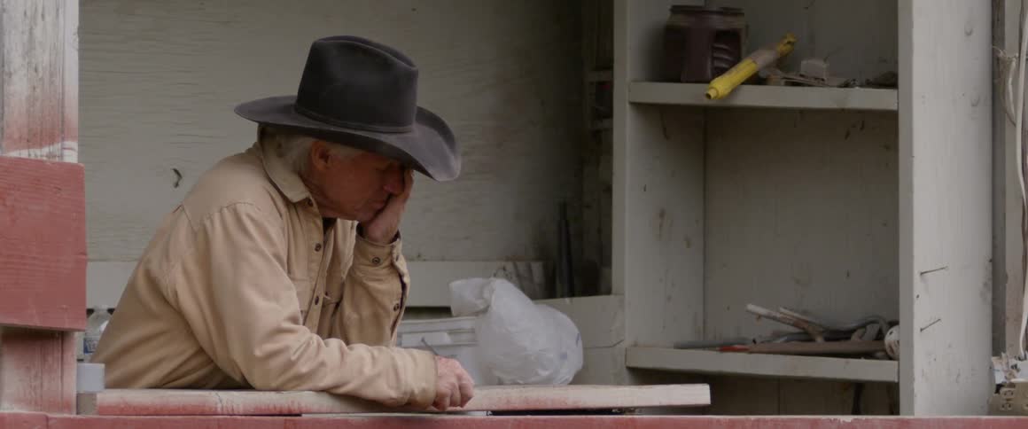 A cowboy rubs his face