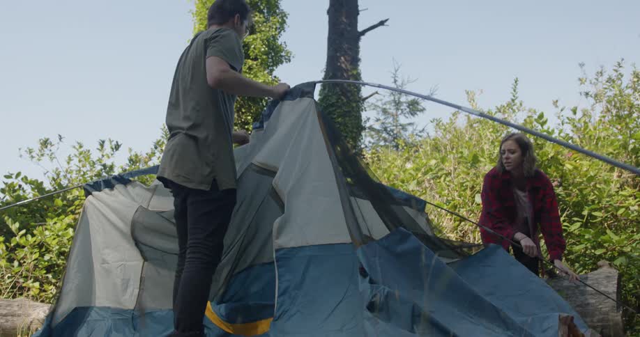 Person sets up a tent on a sunny day
