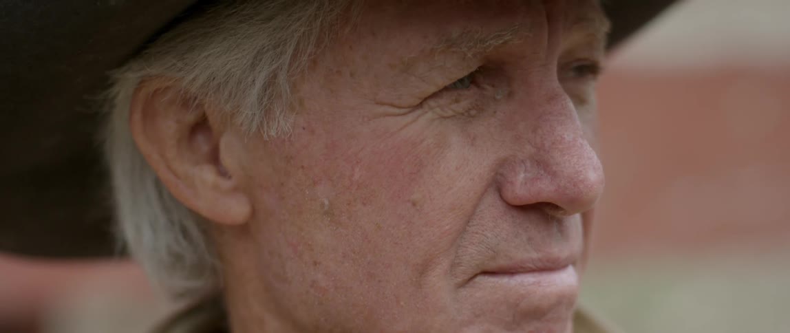 Elderly man wearing a hat looks off to the side