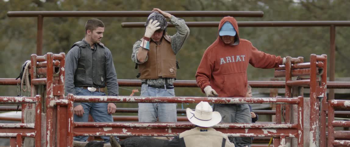 Cowboys stand in a bullpen on a ranch