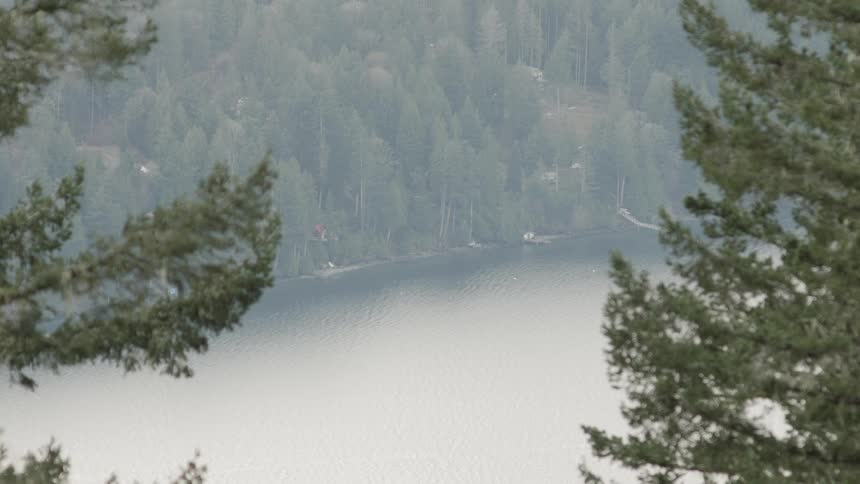 The lake is calm and surrounded by forests on a hill