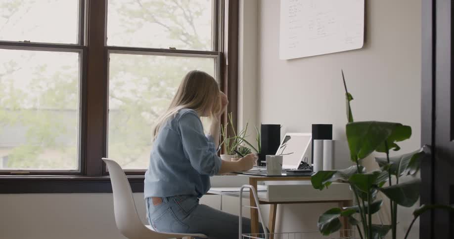 Female College Student Business Owner sitting at her desk writes in a notebook