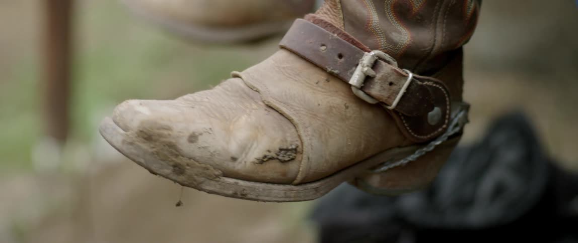 Worn cowboy boots swinging slowly back and forth
