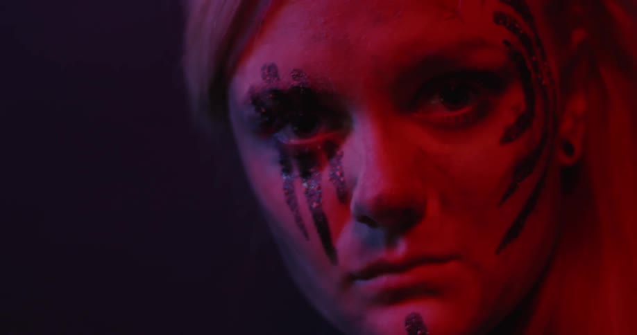 A woman wears paint on her face in the dark