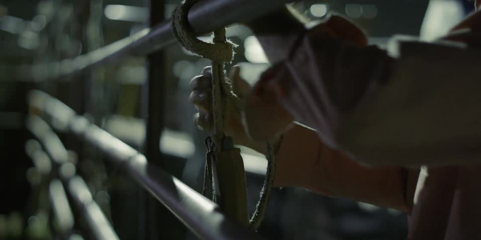A cowboy is tightening some rope in a barn