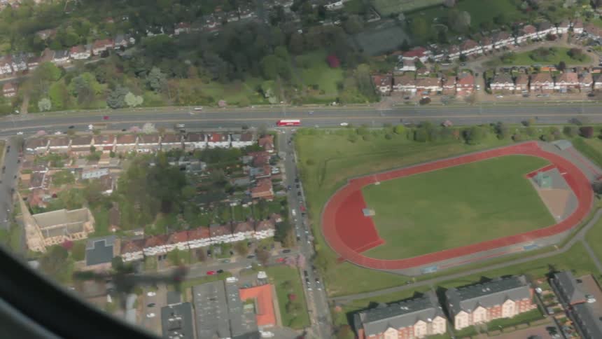 Airplane flies over a sports field and small city