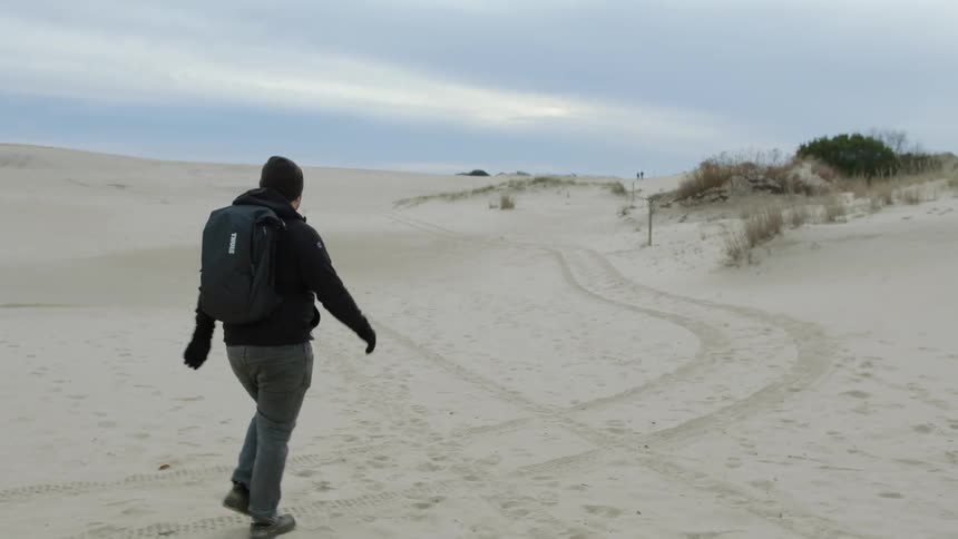 A man is hiking on the beach on a cloudy day