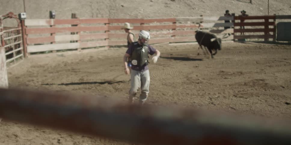 A rider jumps off a bull and runs to the fence