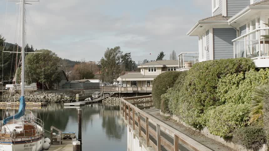 A boat sits docked by a coastal house