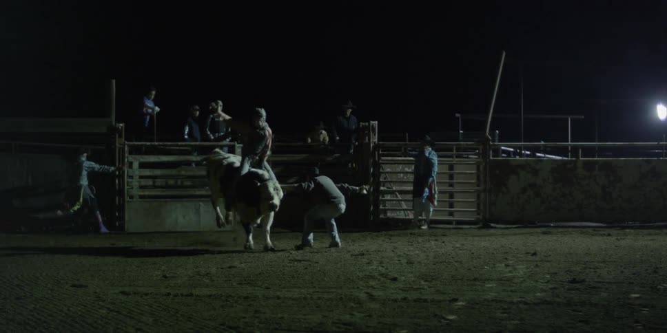 The cowboys open the gate as the rodeo rider storms out on the bull