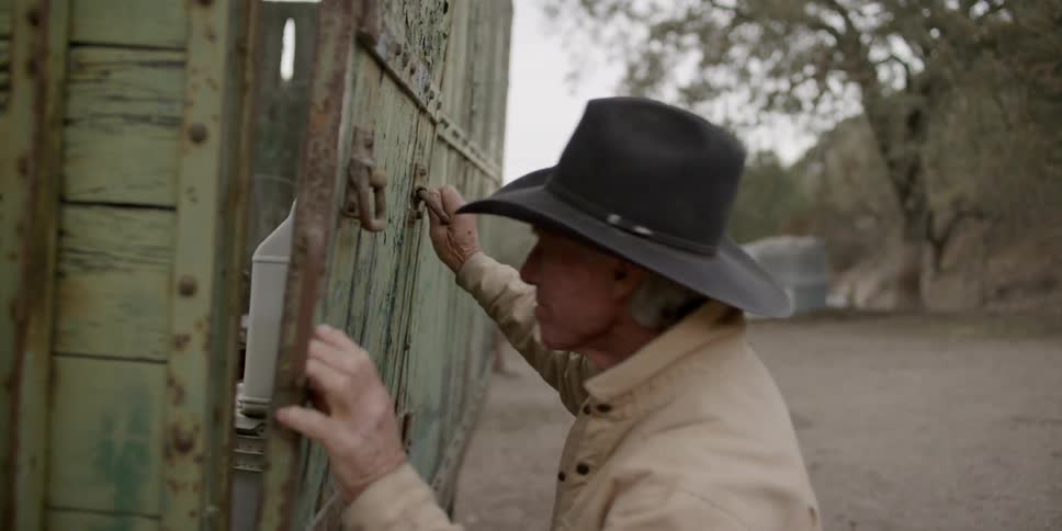 A cowboy struggles to open a truck bed