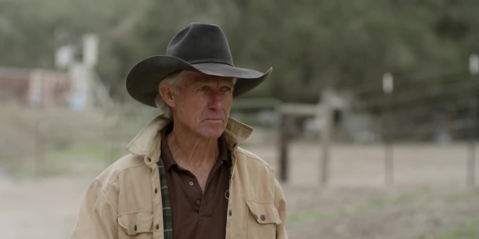 A man in a cowboy hat walks outside
