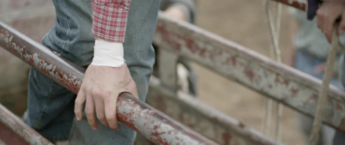 A cowboy climbs onto a bull